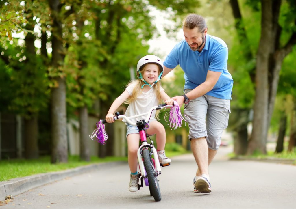 parent qui accompagne son enfant dans l'apprentissage du vélo